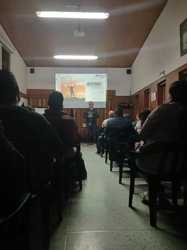 Carlos Sánchez Ortiz dictando una conferencia con apoyo visual en sala.